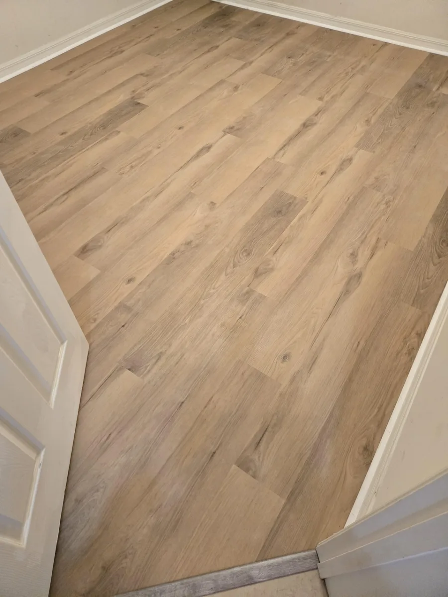 Luxury vinyl plank flooring in a light oak tone across a bedroom