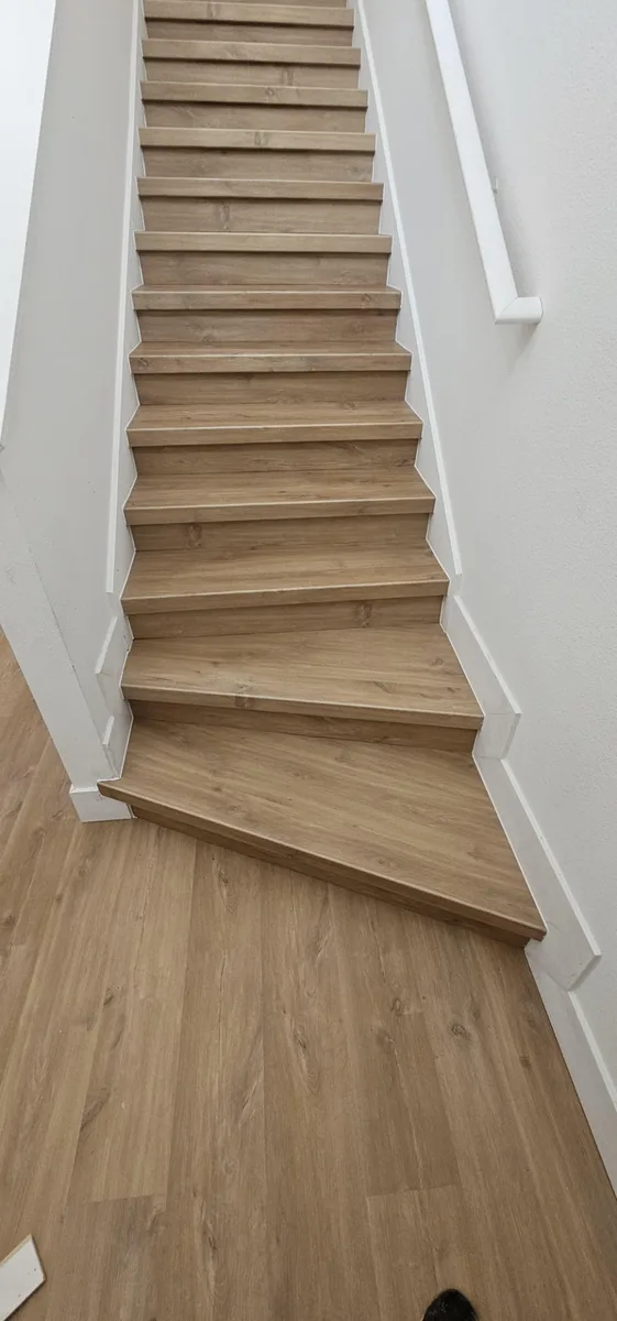 Luxury vinyl plank staircase installation with white risers